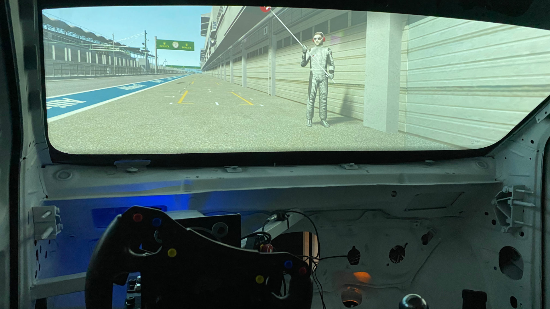 View from the simulator cockpit with a racing steering wheel and projection screen